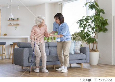 杖をついて立ち上がるシニア女性をサポートする介護スタッフ 123779888
