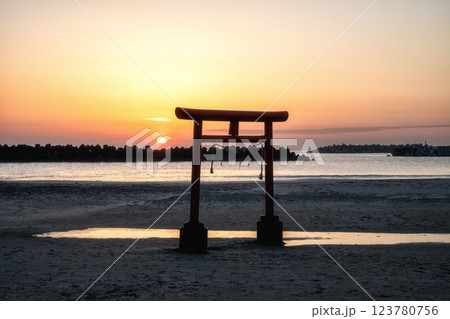日の出を迎える海岸の鳥居と印象的な岩 123780756