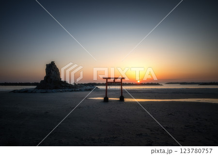 日の出を迎える海岸の鳥居と印象的な岩 123780757