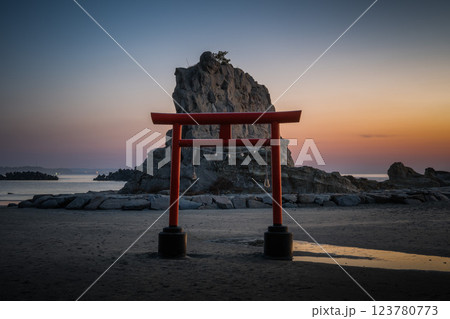 日の出を迎える海岸の鳥居と印象的な岩 123780773