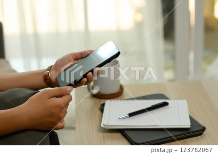 Unrecognizable woman holding a smartphone sitting on sofa 123782067