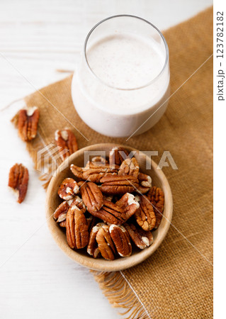 Pecan milk in a glass with raw pecan nuts on wooden table. 123782182