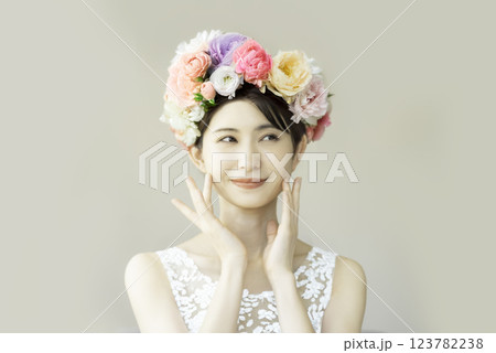 頬に手をあてる花を頭に飾る若い女性のポートレート 123782238
