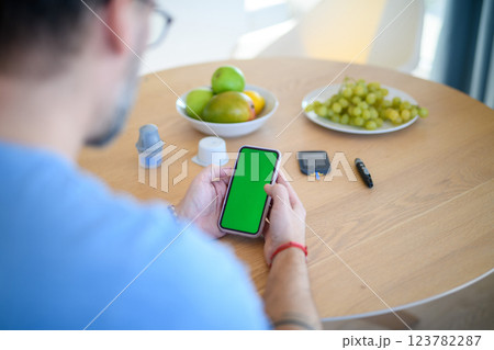 Man is checking blood glucose level using smartphone app. Man is checking blood glucose level using smartphone app. 123782287