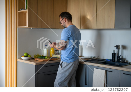 Diabetic man with CGM sensor checking his blood sugar level while making healthy breakfast. Diabetic man with CGM sensor checking his blood sugar level while making healthy breakfast. 123782297