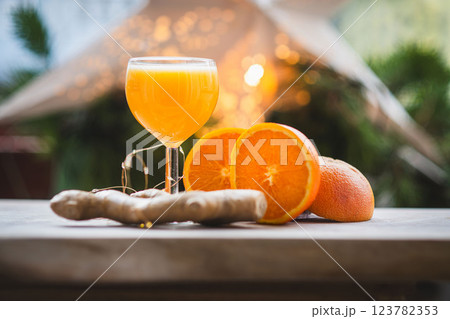 Ginger shot with fresh oranges and ginger root on rustic table 123782353