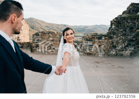 Bride and groom dancing, looking at each other. Wedding couple standing outside near ruins. 123782356