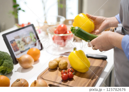 タブレットを見ながら料理をするミドル女性 タブレットを見ながら料理をするミドル女性 123782676