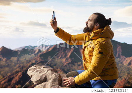 Hiker adventure seeker captures the breathtaking scenic view at the top of mountain, gazes at a distant mountain range and embraces beauty of the wilderness. Joy of discovering wonders. Hiker adventure seeker captures the breathtaking scenic view at the top of mountain, gazes at a distant mountain range and embraces beauty of the wilderness. Joy of discovering wonders. 123783134