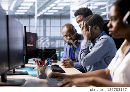 Team of programmers in server farm upset after losing all data after hacker managed to pass firewall. Critical error alert on monitor in data center making IT staff members feel dejected 123783157