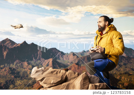 Content creator climbing the mountain peak and filming with his drone, recording professional video on mountain range valley aerial view. Influencer filming his latest travel vlog. Content creator climbing the mountain peak and filming with his drone, recording professional video on mountain range valley aerial view. Influencer filming his latest travel vlog. 123783158