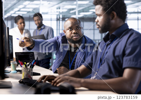 Manager admonishing data center engineer using programming languages to construct algorithms and build applications. Server hub supervisor scolding worker unable to properly optimize code 123783159