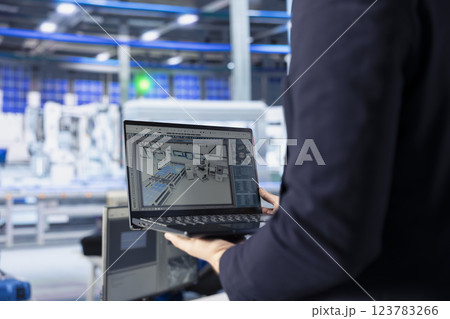 Engineer in photovoltaics factory using tracking software on laptop to diagnose malfunctioning systems. Solar panels manufacturing plant worker uses notebook to reduce downtime 123783266