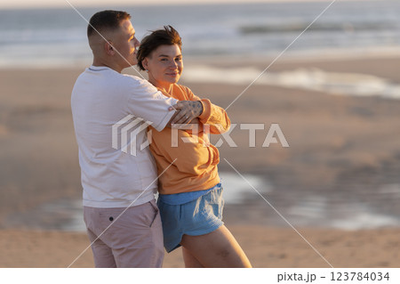 Couple embracing on beach at sunset, enjoying romantic moment 123784034