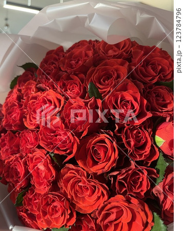 Woman holding luxury bouquet of fresh red roses on light background, closeup Natural background 123784796