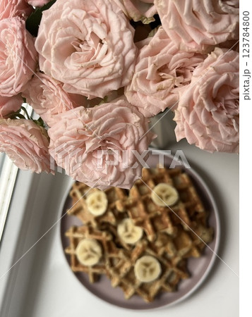 beautiful bouquet of light pink roses on the windowsill with freshly baked homemade waffles decorated with banana breakfast beautiful bouquet of light pink roses on the windowsill with freshly baked homemade waffles decorated with banana breakfast 123784800