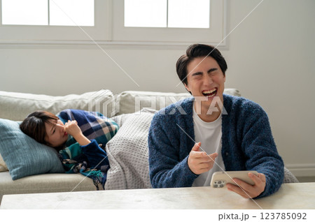 スマホに夢中で看病しない男性 123785092