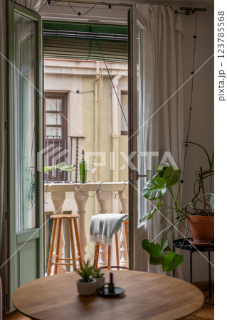 Inviting small balcony setup with stools, a table, and a wine bottle creating a cozy atmosphere Inviting small balcony setup with stools, a table, and a wine bottle creating a cozy atmosphere 123785568