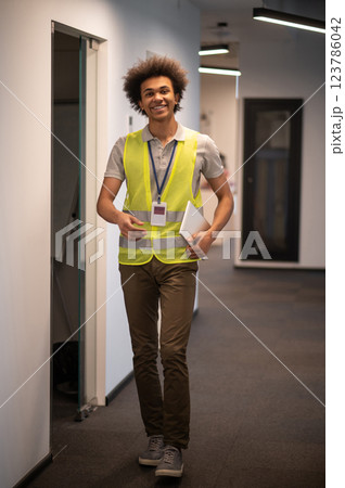 Service man in a yellow vest in the office corridor 123786042