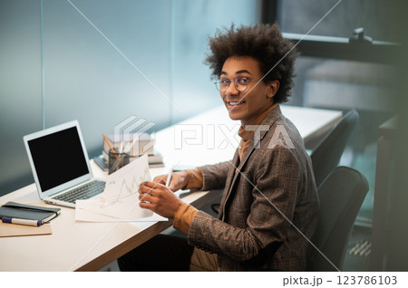 Curly-haired young man sitting at the table in the office 123786103