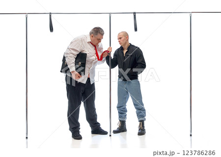 Businessman with loosened tie facing intense stare from younger man in casual attire against white background. Concept of city lifestyle 123786286