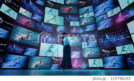 Woman standing in futuristic digital arena with many monitors displaying different sports athletes. Woman standing in futuristic digital arena with many monitors displaying different sports athletes. 123786293