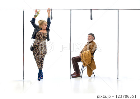 Elderly man looking shocked at woman dancing with bottle inside subway setting against white studio background. Elderly man looking shocked at woman dancing with bottle inside subway setting against white studio background. 123786351