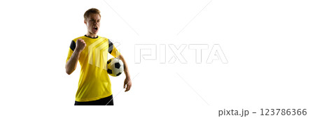 Emotional man, soccer player in yellow jersey holding ball and shouting in excitement, expressing emotions of victory on white background 123786366
