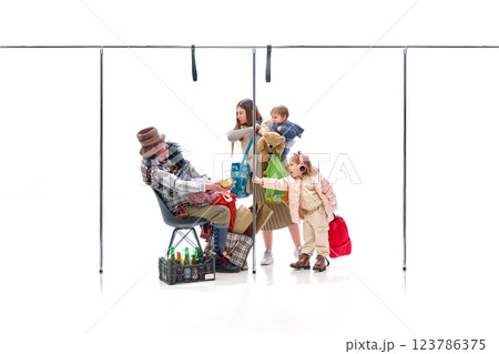 Little girl reaching for bread from homeless man while mother holds baby against white studio background. 123786375