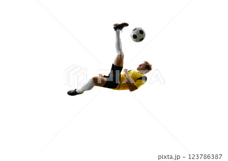 Young man, soccer player executing overhead kick, dynamically kicking ball in air and falling down against white background. Young man, soccer player executing overhead kick, dynamically kicking ball in air and falling down against white background. 123786387