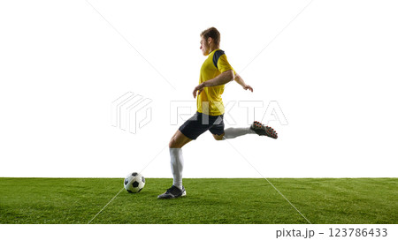 Side view dynamic image of man, soccer player in yellow jersey and black shorts running and dribbling ball, playing against white background 123786433