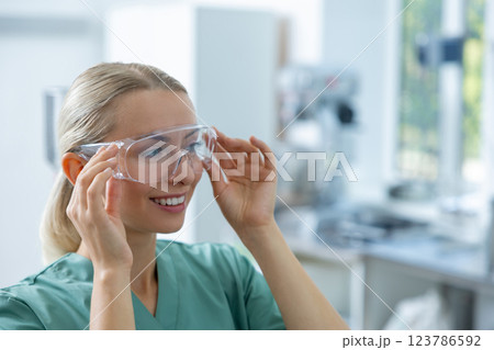 Medical worker in lab coat smiling while standing in clinic laboratory 123786592