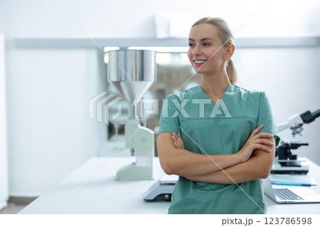Blonde female scientist in green uniform standing indoors in medical laboratory doing research Blonde female scientist in green uniform standing indoors in medical laboratory doing research 123786598