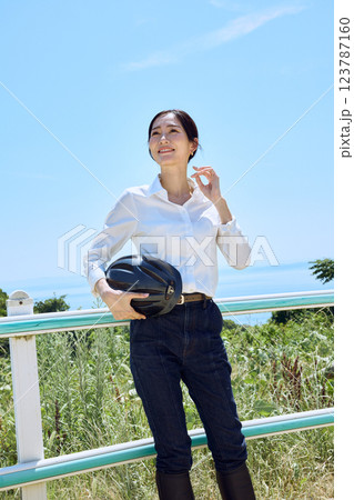 乗馬クラブでヘルメットを持って空を見上げる女性 乗馬クラブでヘルメットを持って空を見上げる女性 123787160