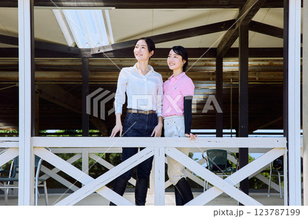 乗馬クラブのテラスから馬場を見る女性 123787199