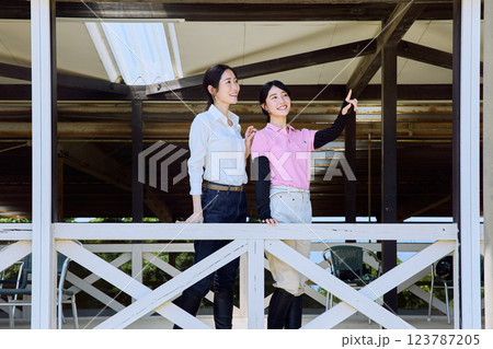 乗馬クラブのテラスから馬場を見る女性 乗馬クラブのテラスから馬場を見る女性 123787205
