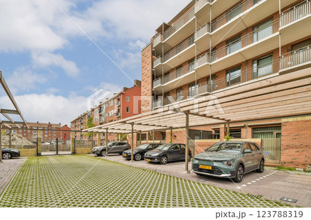 A contemporary residential complex featuring multiple floors adorned with balconies. The parking area is well-organized with spacious spaces visible in the foreground. 123788319