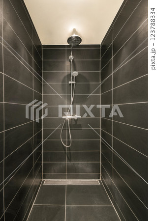 A sleek and elegant modern shower interior featuring dark tiles, clean lines, and a minimalist aesthetic. The design emphasizes simplicity and functionality. 123788334