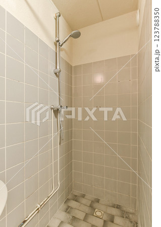 A spacious, minimalist shower area featuring gray tiled walls and flooring, equipped with a simple shower fixture for a clean look. A spacious, minimalist shower area featuring gray tiled walls and flooring, equipped with a simple shower fixture for a clean look. 123788350