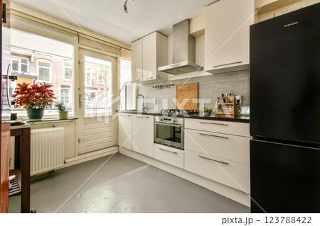 A sleek modern kitchen featuring contemporary appliances and a charming view of the urban landscape through large windows. Bright and functional space. 123788422