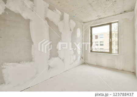 A newly constructed room featuring bare, unfinished walls and a single window allowing natural light to enter, creating a minimalist atmosphere. A newly constructed room featuring bare, unfinished walls and a single window allowing natural light to enter, creating a minimalist atmosphere. 123788437