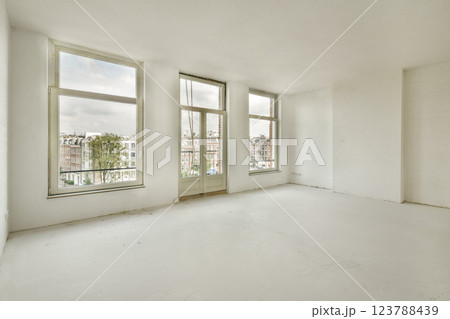 A spacious, minimalist room featuring large windows that invite natural light. The white walls and floor create a clean aesthetic, perfect for various uses. A spacious, minimalist room featuring large windows that invite natural light. The white walls and floor create a clean aesthetic, perfect for various uses. 123788439