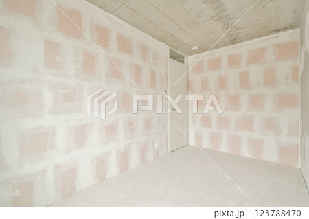 The image showcases an empty room featuring light pink textured walls and a minimalist design, highlighting the unfinished aesthetic and spaciousness. 123788470
