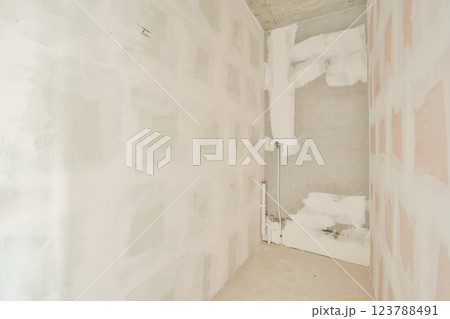 The image showcases an unfinished interior space with light-colored walls and textural patterns. Various materials are visible, creating an industrial feel. 123788491