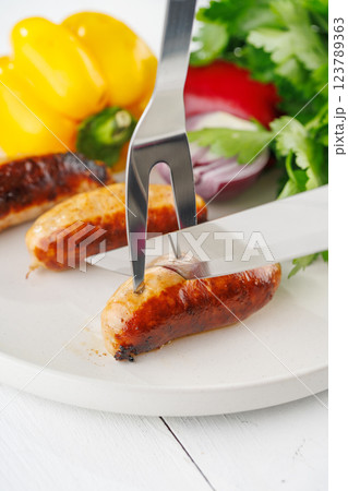 Grilled sausages with vegetables and herbs on a light background Grilled sausages with vegetables and herbs on a light background 123789363