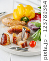Grilled sausages with vegetables and herbs on a light background 123789364