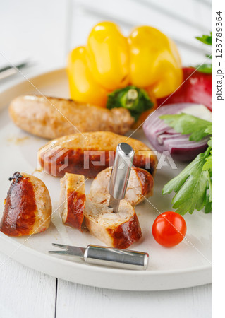 Grilled sausages with vegetables and herbs on a light background Grilled sausages with vegetables and herbs on a light background 123789364