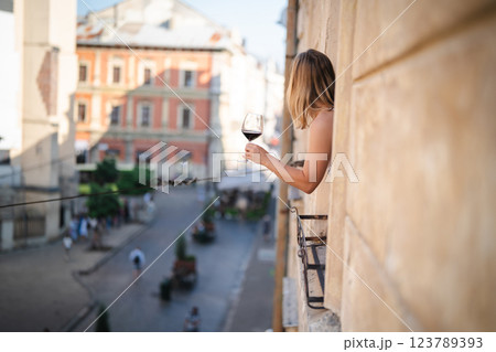 Young woman with glass of red wine on the balcony in the city 123789393