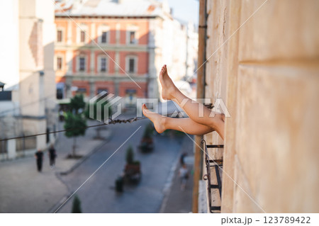 Close-up of female legs with red shoes of high heels. The woman is raising her feet through the window 123789422