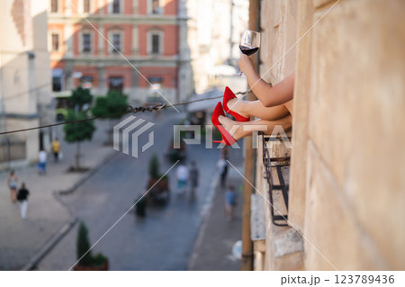 Close-up of female legs with red shoes of high heels. The woman is raising her feet through the window 123789436